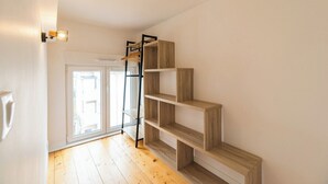 A room with a wooden floor, a staircase with a black metal railing, and a white wall.