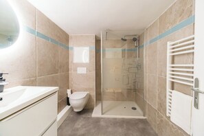 Een moderne badkamer met douche, toilet en wastafel.