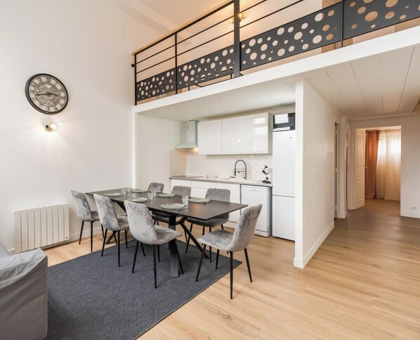 Um apartamento moderno com área de refeições, cozinha e escada com corrimão estampado em bolinhas.