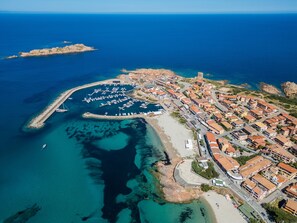 Vue aérienne d’une ville côtière avec un port de plaisance, des bâtiments et une église imposante.
