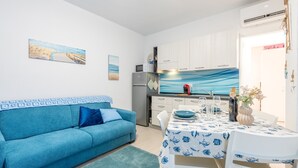 Un espacio habitable compacto con kitchenette, comedor y sofá.