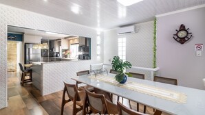 A modern kitchen with a central island, wooden chairs, and a dining table with a lace table runner. - Apt w/ Balcony, 3 Bedrooms Close to Beach Rsu3842 (Penha)