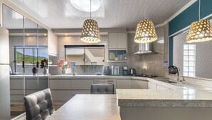 A modern kitchen with a central island, pendant lights, and a view of the outdoors. - Apt w/ Balcony, 3 Bedrooms Close to Beach Rsu3842 (Penha)