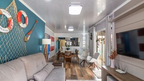 A modern living room with a sofa, TV, and a dining area with chairs and a table. - Apt w/ Balcony, 3 Bedrooms Close to Beach Rsu3842 (Penha)