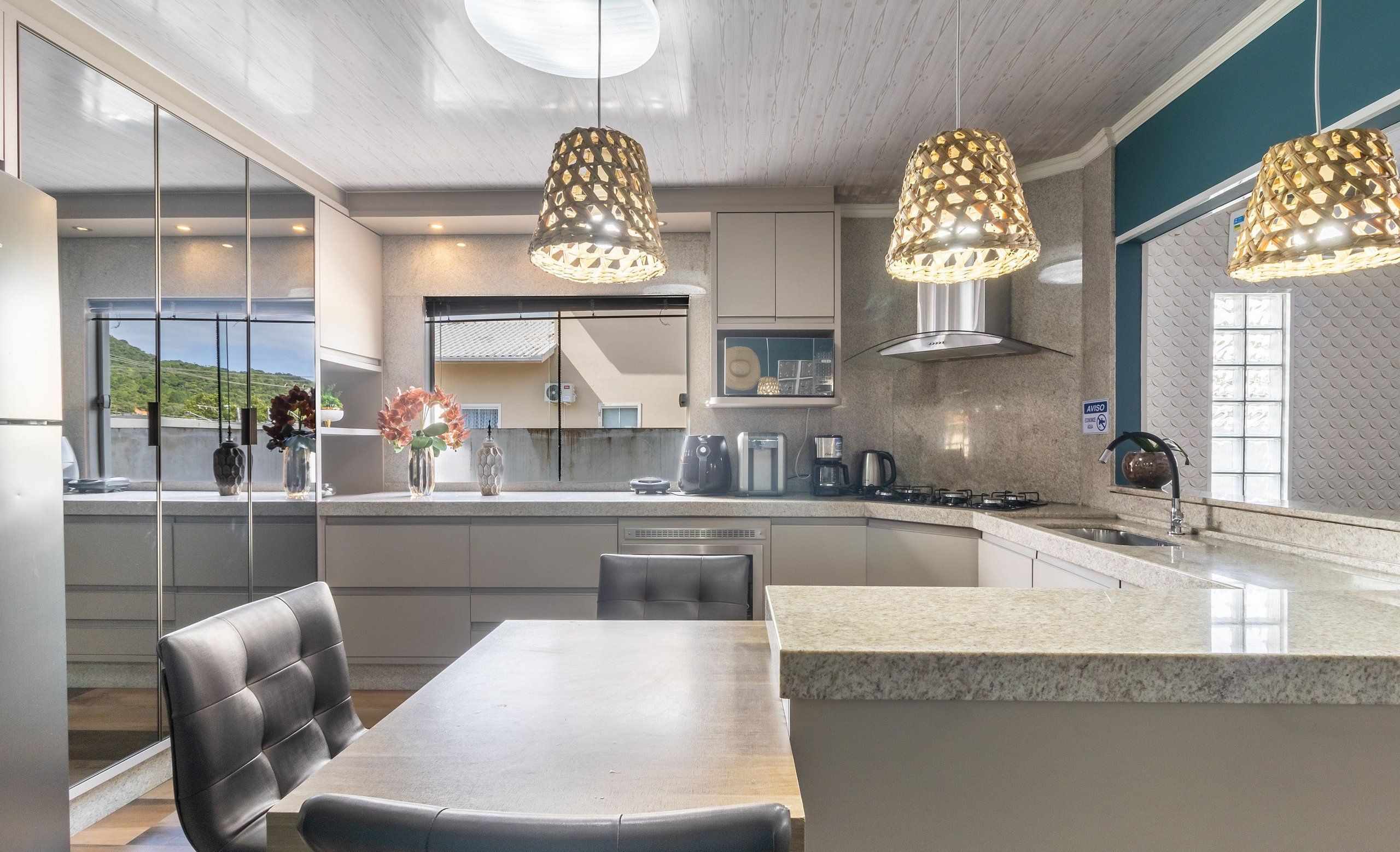 Een moderne keuken met een centraal eiland, hanglampen en uitzicht op de omgeving.