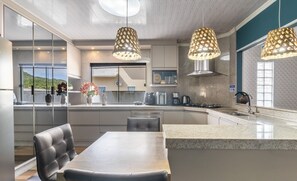 A modern kitchen with a central island, pendant lights, and a view of the outdoors. - Apt w/ Balcony, 3 Bedrooms Close to Beach Rsu3842 (Penha)