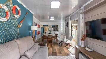 Una sala de estar moderna con un sofá, televisor y un comedor con sillas y una mesa.