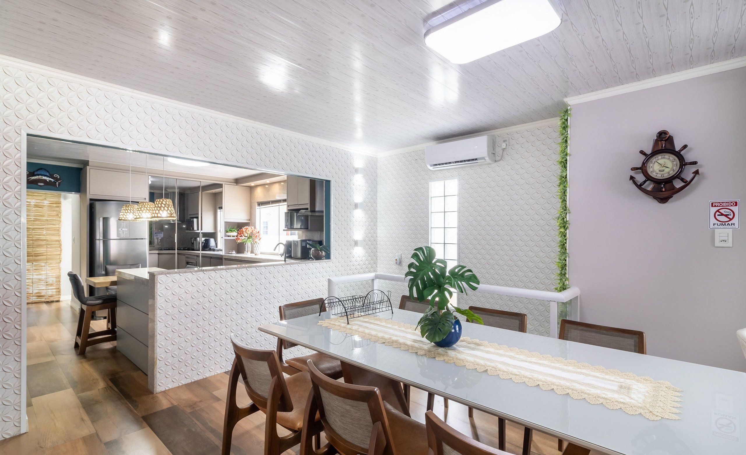 Una cocina moderna con una isla central, sillas de madera y una mesa de comedor con camino de mesa de encaje.