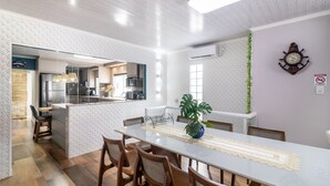 A modern kitchen with a central island, wooden chairs, and a dining table with a lace table runner. - Apt w/ Balcony, 3 Bedrooms Close to Beach Rsu3842 (Penha)