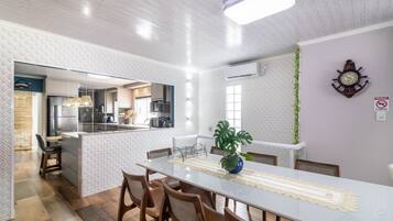 Una cocina moderna con una isla central, sillas de madera y una mesa de comedor con camino de mesa de encaje.