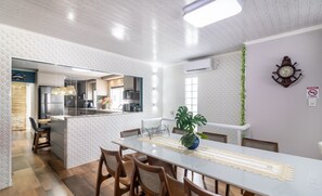 A modern kitchen with a central island, wooden chairs, and a dining table with a lace table runner. - Apt w/ Balcony, 3 Bedrooms Close to Beach Rsu3842 (Penha)