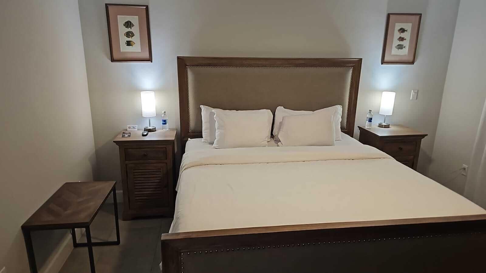 Ein ordentlich eingerichtetes Hotelzimmer mit einem großen Bett, zwei Nachttischen und gerahmten Bildern an den Wänden.