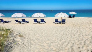 A beach with white umbrellas labeled "TIDES" and blue lounge chairs. - The Tides Grace Bay (Providenciales)