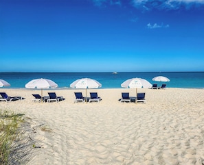 Perto da praia, areia branca, espreguiçadeiras, guarda-sóis