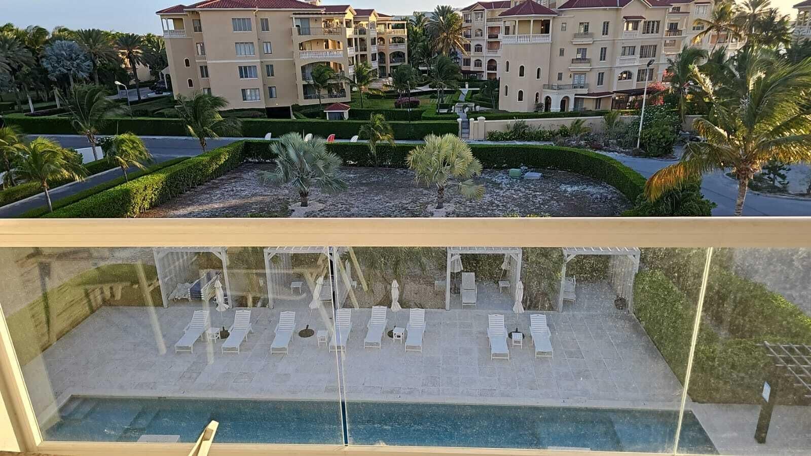 A poolside area with sun loungers and a view of a multi-story building with balconies.