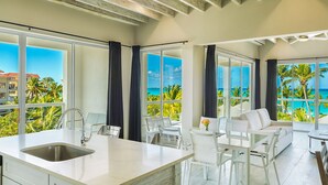 A modern kitchen with a large island, white furniture, and large windows offering ocean views. - The Tides Grace Bay (Providenciales)