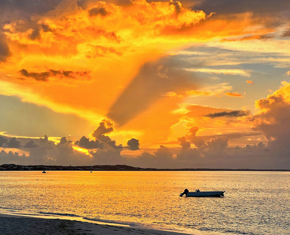 Un barco sobre aguas tranquilas con el atardecer al fondo.