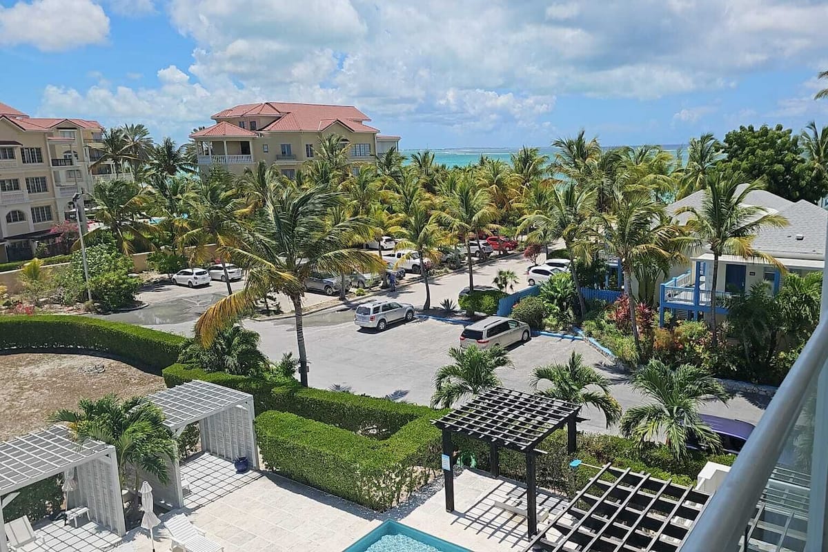 A resort with a pool area, palm trees, and a view of the ocean.