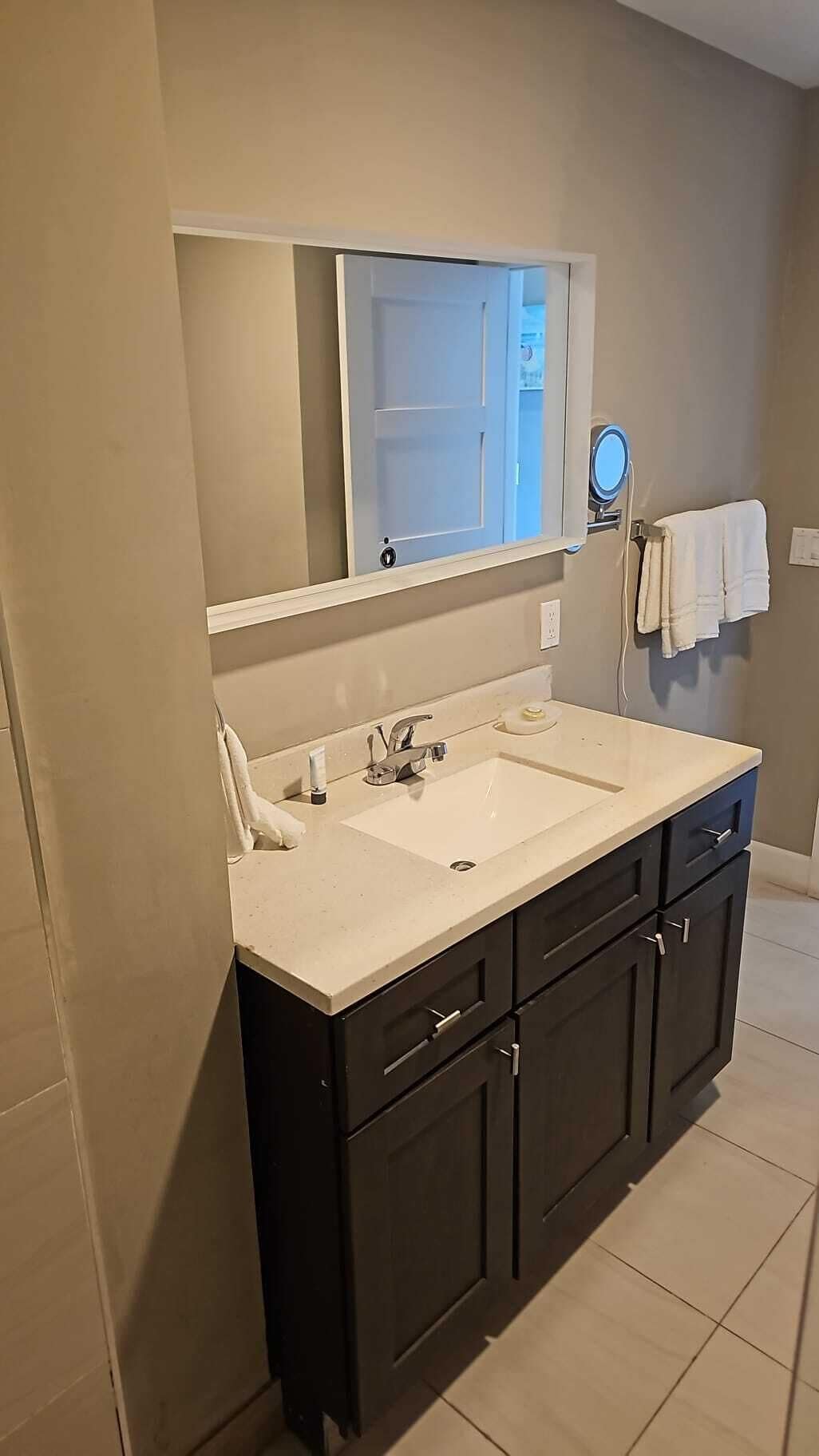 Une salle de bain avec un double vasque, des meubles sombres, un miroir et un porte-serviettes.