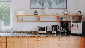 A kitchen with wooden cabinets, a granite countertop, a coffee maker, a kettle, and a toaster. - Family-friendly vacation home - 300m to the sea (Wurster Nordseeküste)