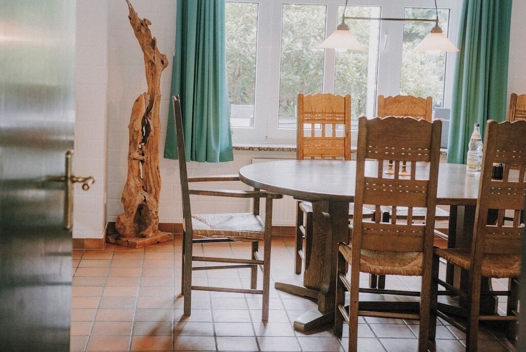 A dining area with a round table, wooden chairs, and a rustic wooden sculpture.