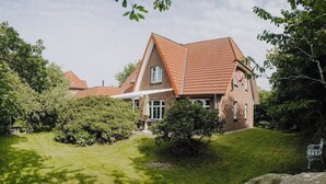 A large brick house with a steeply pitched roof and a well-maintained lawn. - Family-friendly vacation home - 300m to the sea (Wurster Nordseeküste)