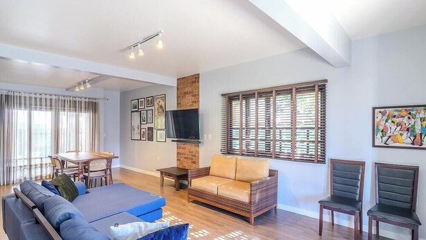 Una sala moderna con sofá, mesa de centro, televisor y un comedor con mesa y sillas.