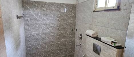 A bathroom with a shower, toilet, and sink, featuring marble walls and a black countertop.