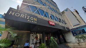 Un hotel llamado 'Hotel Horizon Plaza' con una fachada moderna de vidrio, una tienda Levi's en la planta baja y un cartel que indica el nombre del hotel.