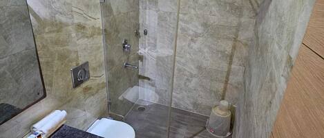 A bathroom with a marble shower, a sink, and a toilet.