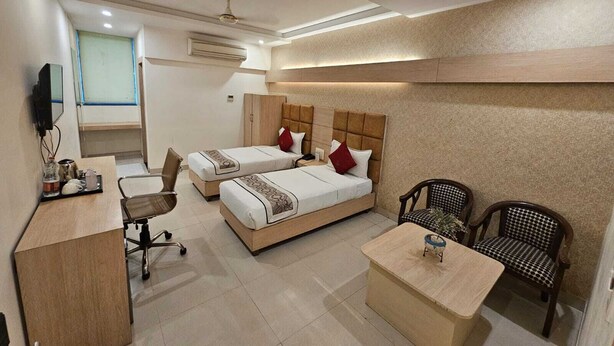 Una habitación de hotel con dos camas, un escritorio, una silla y un televisor.