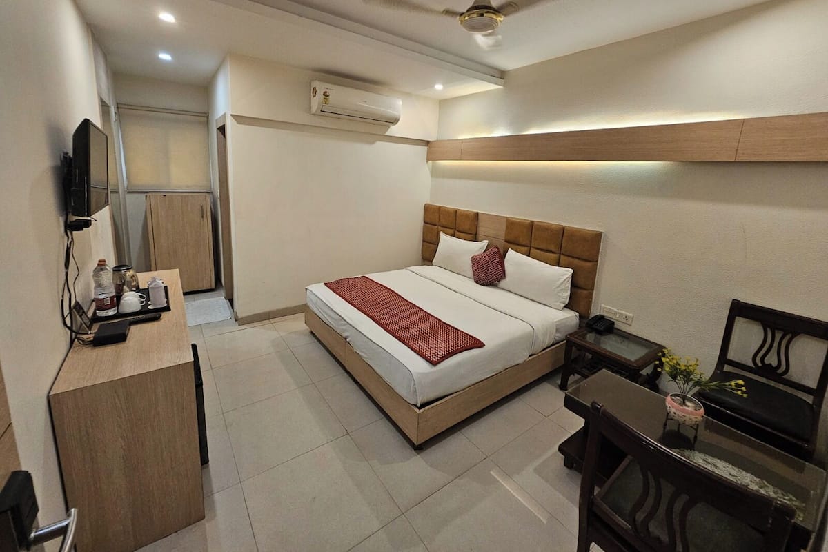 A hotel room with a bed, bedside table, chair, desk, and a ceiling fan.