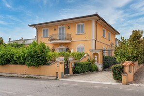 A two-story house with a balcony, a gated entrance, and a well-maintained garden.