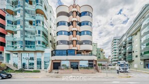 Un immeuble à plusieurs étages doté d’un atrium central, de grandes fenêtres et d’une enseigne indiquant qu’il s’agit d’une zone résidentielle.