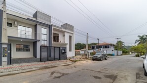 En bostadsgata med moderna hus, en grind vid infarten och en parkerad bil.