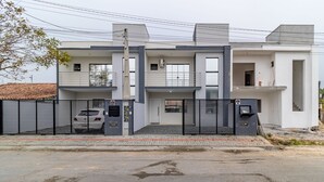 Ett modernt hus i två våningar med en grind vid infarten, en balkong och ett synligt garage.