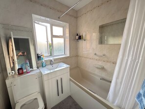 Une salle de bain avec une baignoire, un lavabo, un miroir et une fenêtre.