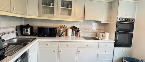 A kitchen with white cabinets, a microwave, a toaster, and a dishwasher.