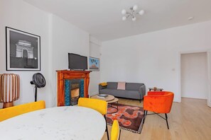 A living room with a fireplace, a sofa, a dining table, and a TV.