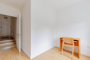 Ein Zimmer mit Schreibtisch und Stuhl aus Holz, einer weißen Tür und einem Holzboden.