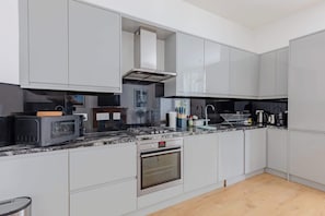Una cocina moderna con armarios grises, horno empotrado, microondas y cocina a gas.