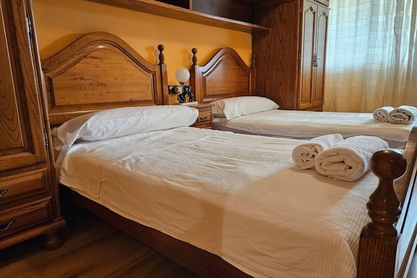 A double bed with a wooden headboard, a nightstand with a lamp, and a wardrobe.