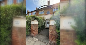 A residential property with a brick facade, a visible entrance gate, and a number plaque indicating the address.