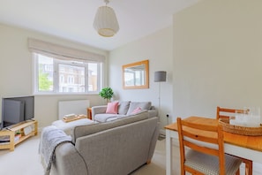A modern living room with a sofa, TV, and dining area.