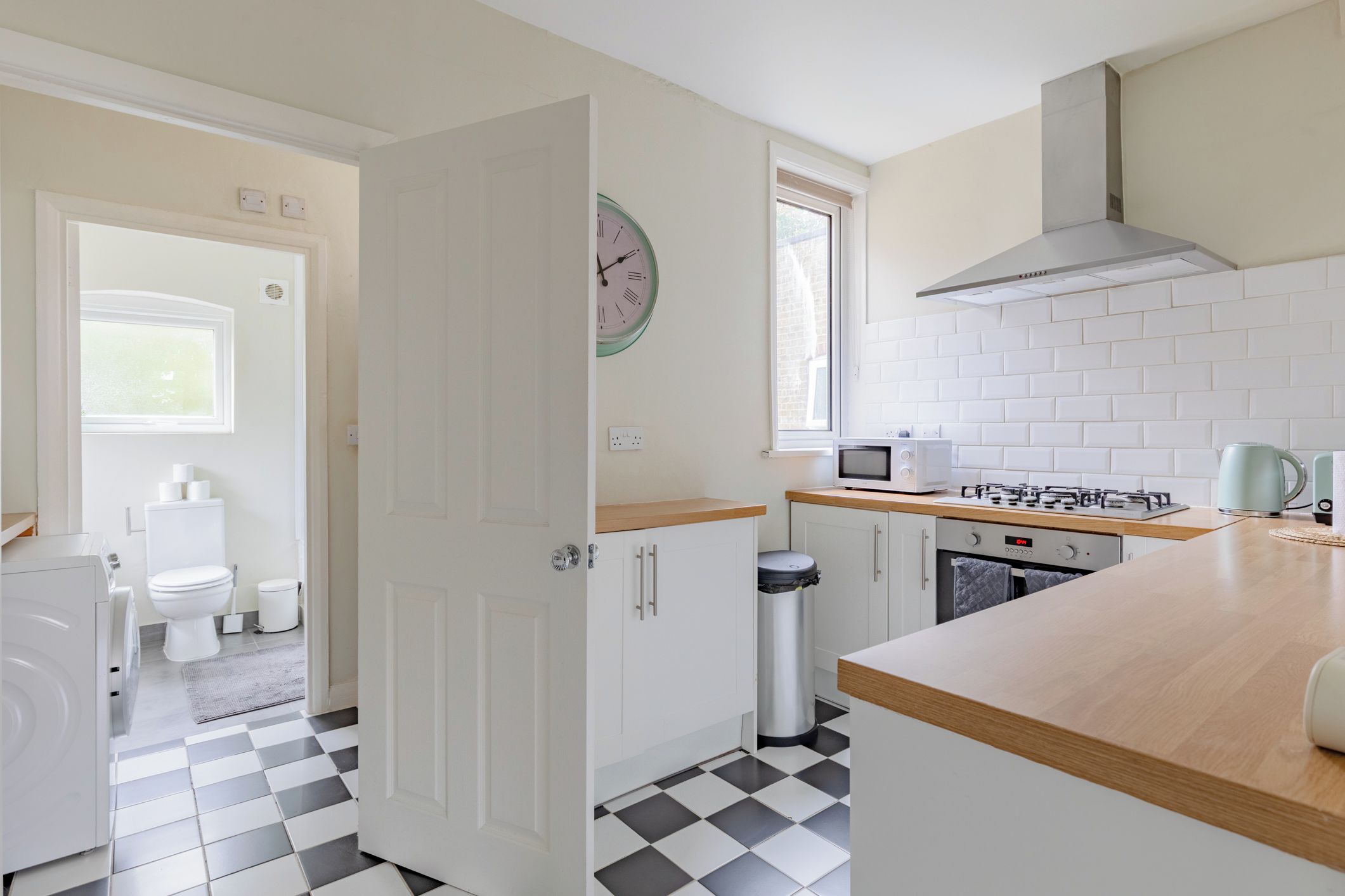 A modern kitchen with white cabinets, a microwave, a stove, and a window.