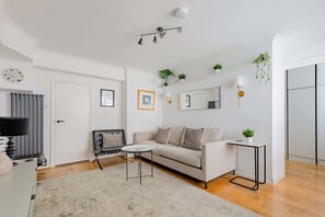 Una sala de estar moderna con un sofá, una mesa de centro y una mesita auxiliar con una planta.