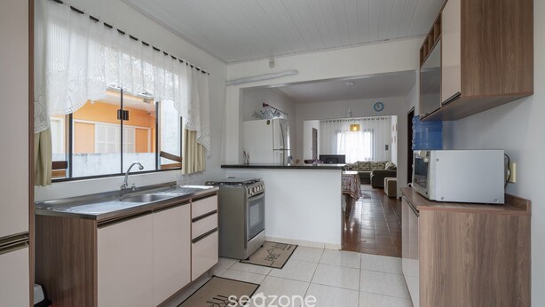 A modern kitchen with a central island, built-in appliances, and a view into the dining area. - 3BR Home w/ BBQ 100m From Beach Rpr056 (Penha)