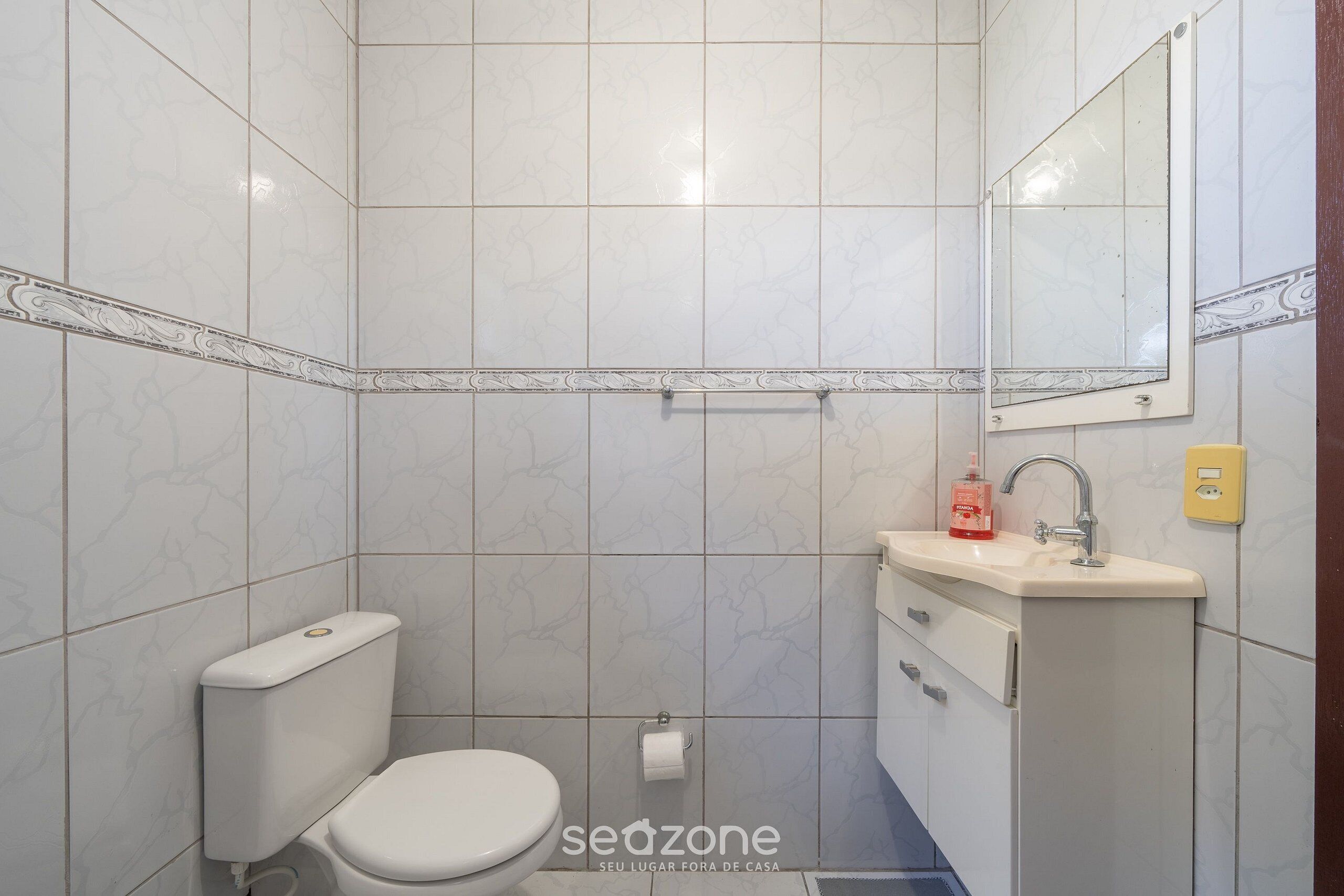 A bathroom with a toilet, sink, and mirror.