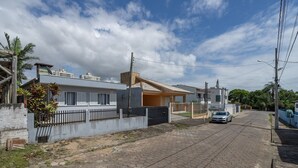 A residential street with houses, a car parked on the side, and a clear sky. - 3BR Home w/ BBQ 100m From Beach Rpr056 (Penha)