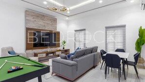 Un salon moderne avec une table de billard, un canapé gris, une table à manger et des chaises.